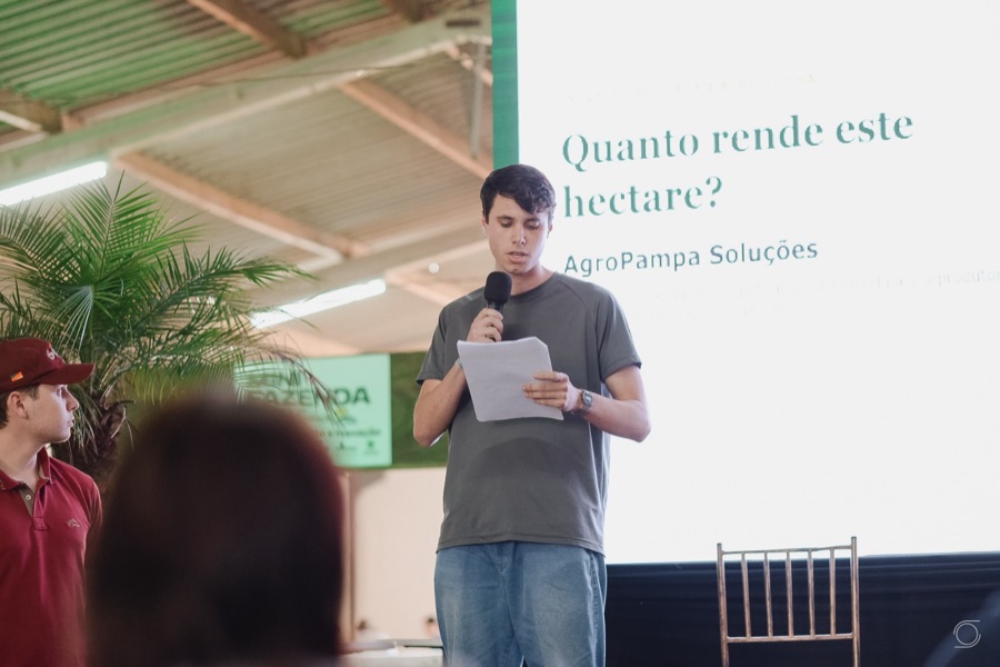Estudante apresenta o pitch da AgroPampa diante do telão com a pergunta Quanto rende este hectare?